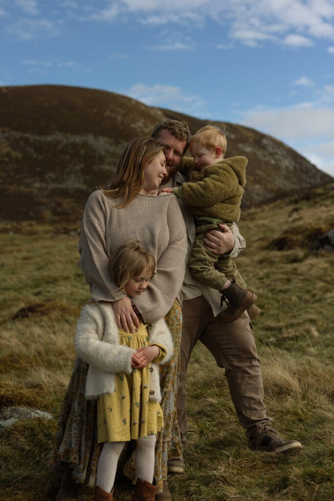 family cuddle together in the scottish highlands