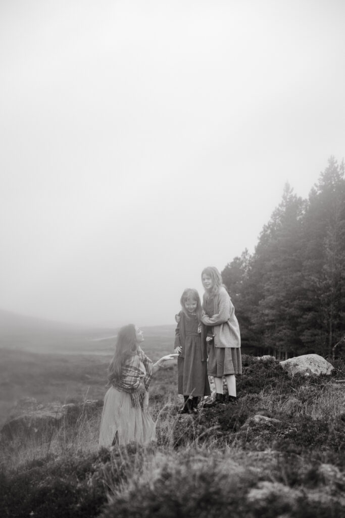 Mother and daughters cuddling during a winter photoshoot in the Scottish Highlands
