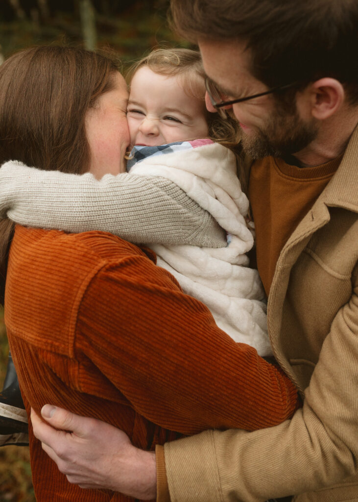 Family cuddling during a winter photoshoot in the Scottish Highlands