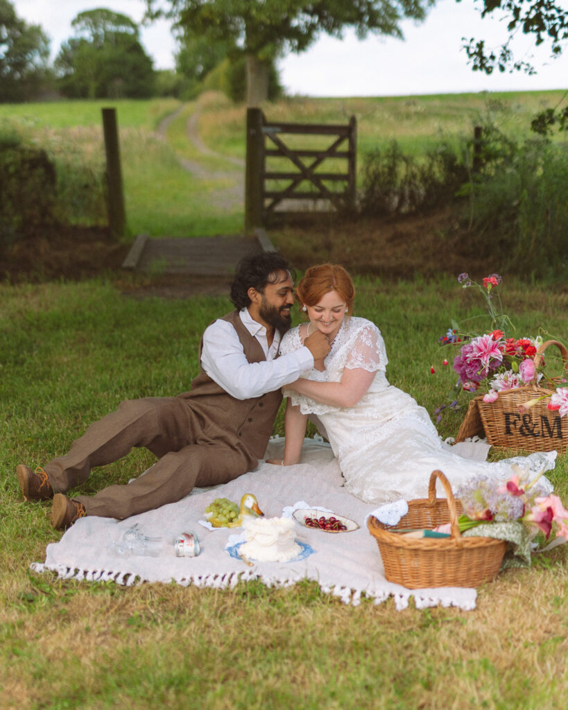 bride and groom laugh together while having a picnic on their elopement day